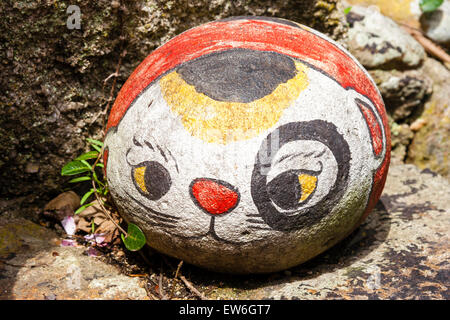 Japan, Onomichi. Runder Stein mit Gesicht und Körper einer Katze auf dem Boden vor dem Restaurant, Schild für Treffpunkt für die Begrüßung der Kunden. Stockfoto