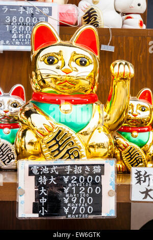 Japan, Kurashiki. Glücklicher Katzen-Shop, Anzeige außerhalb des Ladens von goldfarbenem Maneki, glücklichen Katzen, mit Armen, die dazu erhoben werden, Kunden im Laden zu belocken. Stockfoto