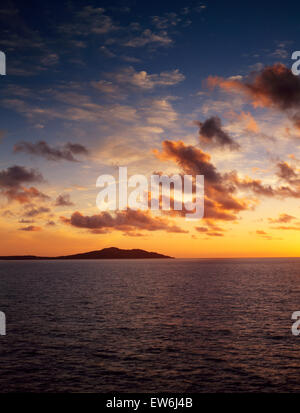Aussehende SW in Holyhead Bucht von Porth Swtan (Church Bay), Anglesey mit Holyhead Mountain vor einem Sonnenuntergang Himmel abhebt. Stockfoto
