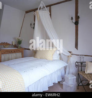 Coronet mit weißen Voile Vorhänge über Bett mit weißen Bettdecke in neunziger Jahre Ferienhaus Schlafzimmer Stockfoto
