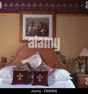 Bild an Wand oben geschnitzt Kiefer Bett mit samt Fleur Motiv Kissen in den neunziger Jahren Schlafzimmer mit perforierten Rand Stockfoto