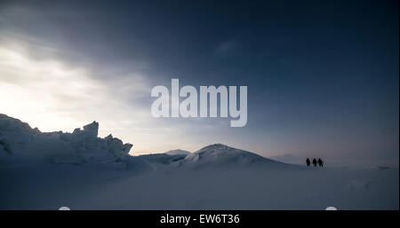 Drei Menschen besichtigen die Scott Base Druck Grate in der Abenddämmerung mit Mount Erebus im Hintergrund sichtbar. Stockfoto