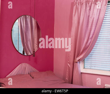 Runder Spiegel über dem Bett in rosa neunziger Jahre Wirtschaft Schlafzimmer Stockfoto