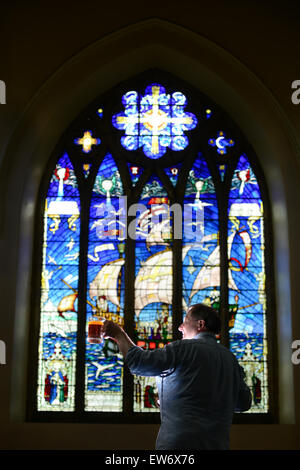 Ein Mann, einen Pint Bier vor einem Buntglas-Fenster heben. Bild: Scott Bairstow/Alamy Stockfoto