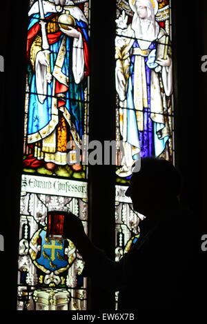 Ein Mann, einen Pint Bier vor einem Buntglas-Fenster heben. Bild: Scott Bairstow/Alamy Stockfoto