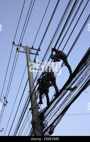 Elektrische Kabel-Monteure in einer gefährlichen Situation über einer Stadt Straße in Pattaya Thailand arbeiten Stockfoto