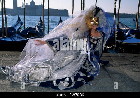 Ein einheimischer tragen traditionelle Masken und Gewändern sitzen am Kai beim Karneval in Venedig für nur zur redaktionellen Nutzung Stockfoto