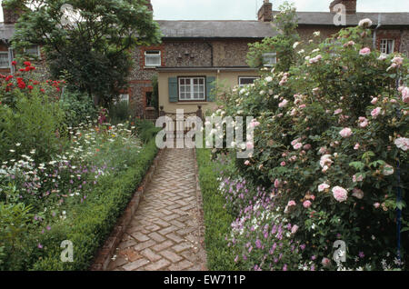 Backstein Fischgrät gepflasterten Weg mit Box Rand zwischen den Grenzen mit rosa Rosen im Bauerngarten Stockfoto