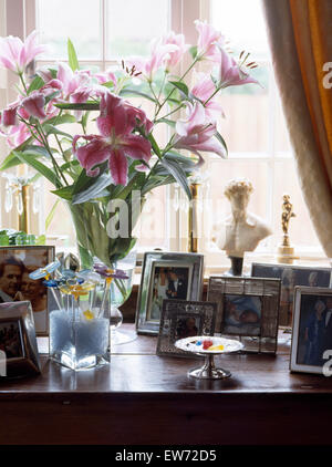 Vase rosa Lilien und eine Sammlung von Fotografien auf Schminktisch Stockfoto