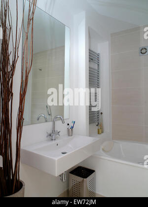Große Spiegel über dem rechteckigen weißen Becken neben Bad im kleinen Badezimmer Stockfoto