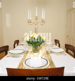 Silberne Kerzenständer und Vase mit gelben Rosen auf Tisch mit weißen Tuch legen Sie für das Abendessen im Speisesaal Stadthaus Stockfoto