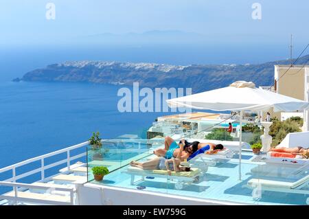 Menschen auf Liegestühlen mit Blick auf die Caldera mit dem Dorf Oia im Hintergrund, Imerovigli, Santorin, Griechenland Stockfoto