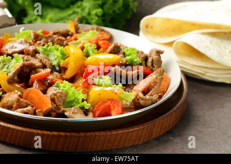 Beef Fajitas mit bunten Paprika in die Pfanne auf einem Holztisch Stockfoto