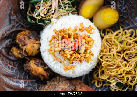 Indonesische Nasi Campur mit gebratenem Huhn, Nudeln, Eiern, Tempeh und Gemüse. Stockfoto