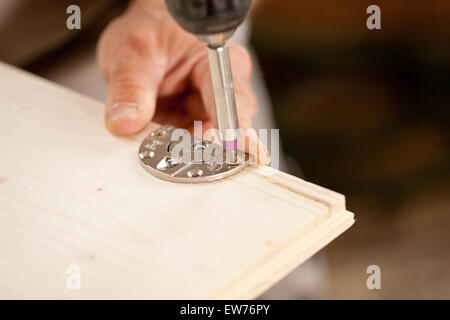 flacher Schärfentiefe und konzentrieren sich auf ein Detail eines Fahrer-Bits und die Hand eines Tischlers, indem ein Scharnier auf eine hölzerne handgemachte f Stockfoto