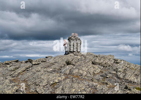 Norwegen. Eine blonde Teenager steht neben einem Gipfel Cairn in die zerklüftete Berglandschaft über Vinstra und Lillehammer Stockfoto