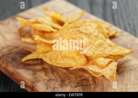 Haufen von Tortilla-Chips auf Oliven Brett auf Holztisch Stockfoto