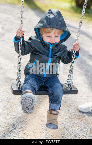 Kleiner Junge mit Haube auf einer Schaukel Stockfoto