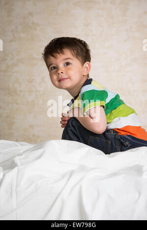 Kleiner Junge sitzt auf einem Bett Stockfoto