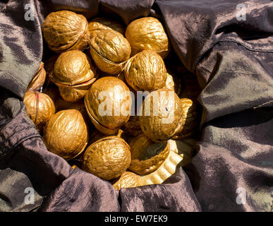 Haufen von golden bemalte Walnüsse ruht auf schwarzem satin in natürlichem Sonnenlicht Stockfoto