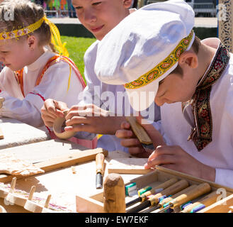 Gruppe von Kleinkindern in weißen russischen Nationaltracht Arbeit auf carving auf einer Messe in Ufa Holzschnitzerei Juli 2015 Stockfoto