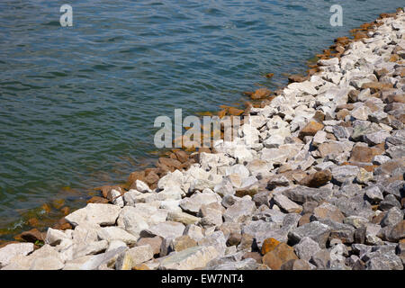 Stein-Ufer des künstlich angelegten See mit großen Natursteinen und wellige Wasser. Stockfoto