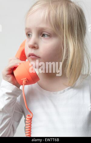 Mädchen, die mit einem traditionellen Telefon sprechen Stockfoto