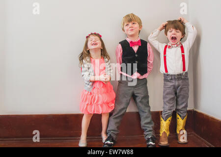 Drei Kinder in smarter Kleidung verkleidet, die herumwirren Stockfoto