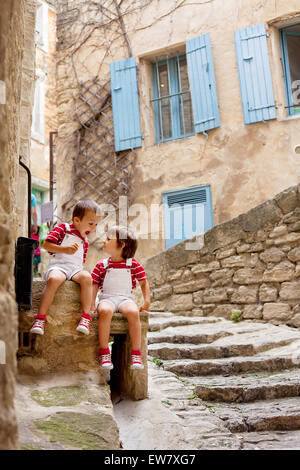 Zwei entzückende Kinder, sitzen auf der Straße Felsen, lächelnd, Eis essen, sahen einander Stockfoto