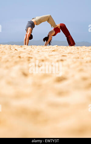 Mann und Frau auf einem Felsvorsprung am North Curl Curl, einer von Sydneys Nordstrände Yoga zu praktizieren. Sydney, N Stockfoto
