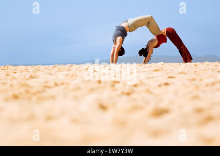 Mann und Frau auf einem Felsvorsprung am North Curl Curl, einer von Sydneys Nordstrände Yoga zu praktizieren. Sydney, N Stockfoto