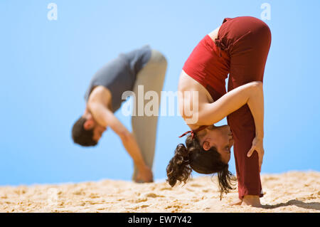 Leyla Brooks und James Fellows praktizieren Yoga auf einem Felsvorsprung am North Curl Curl, einer von Sydneys Nordstrände. Sydney, N Stockfoto