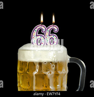 Beleuchteten Geburtstagskerzen im Krug Bier für 66. Geburtstag isoliert auf schwarz. Stockfoto