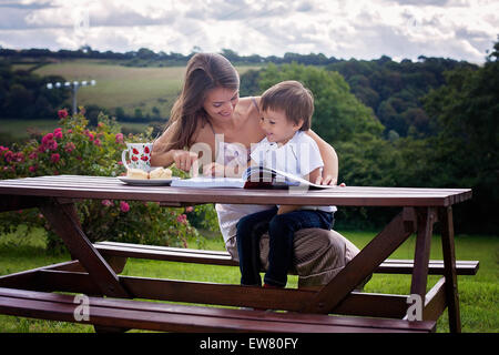 Mutter und Sohn, ein Buch im Freien, Sommertag, süßes Gebäck Essen Stockfoto