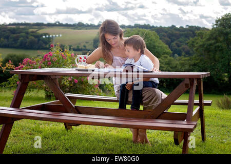 Mutter und Sohn, ein Buch im Freien, Sommertag, süßes Gebäck Essen Stockfoto