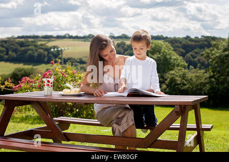 Mutter und Sohn, ein Buch im Freien, Sommertag, süßes Gebäck Essen Stockfoto