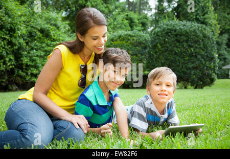 Junge alleinerziehende Mutter mit zwei Jungen spielen auf iPad Tablet in Hof Stockfoto