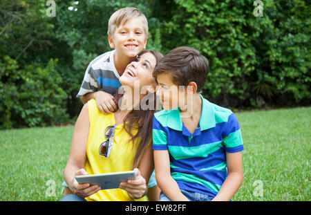 Junge alleinerziehende Mutter mit zwei Jungen spielen auf iPad Tablet in Hof Stockfoto