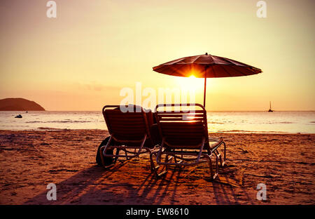 Vintage Instagram stilisiert, Sonnenschirm und liegen am Strand bei Sonnenuntergang. Konzept für Urlaub und Erholung. Stockfoto