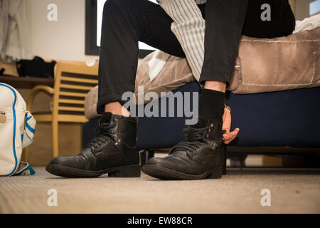 Nahaufnahme der Mann zu Hause anziehen der Schuhe. Blick auf seine Füße auf dem Boden des Schlafzimmers Stockfoto