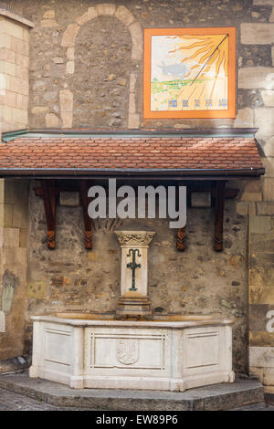 Brunnen und Sonnenuhr auf der Rückseite einer kleinen Kirche in der Altstadt von Genf, Schweiz Stockfoto