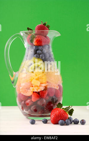 Frischer Fruchtsaft Konzept mit Regenbogen Farbe Früchten wie Kirschen, Erdbeeren, Himbeeren, Mandarinen Segmente, Kiwis, Stockfoto