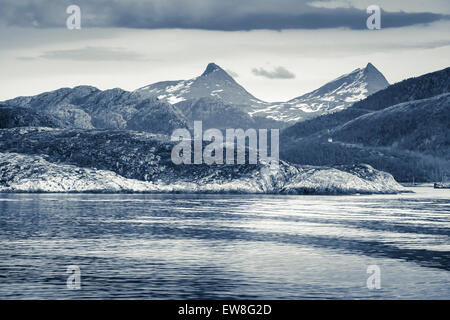 Frühling norwegische Landschaft mit Meeresküste und die Berge mit Schnee. Blau getönten schwarz-weiß Foto, Vintage-Stil-filter Stockfoto