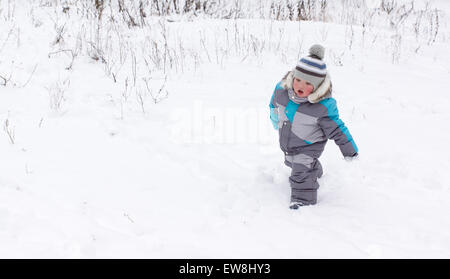 kleiner Junge in Overall und Mütze Spaziergänge im Schnee Stockfoto