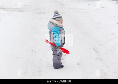 kleiner Junge in Overall und Mütze Spaziergänge im Schnee Stockfoto