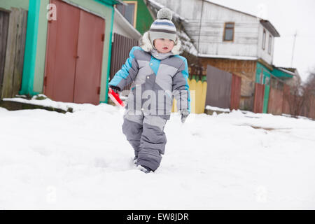 kleiner Junge in Overall und Mütze Spaziergänge im Schnee Stockfoto