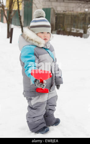 kleiner Junge in Overall und Mütze Spaziergänge im Schnee Stockfoto