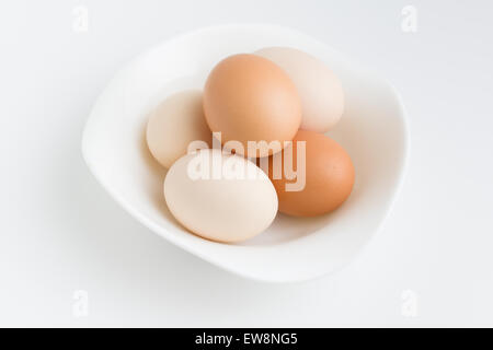 mehreren rohe Eiern liegen auf einer Platte, die auf einem weißen Hintergrund steht Stockfoto