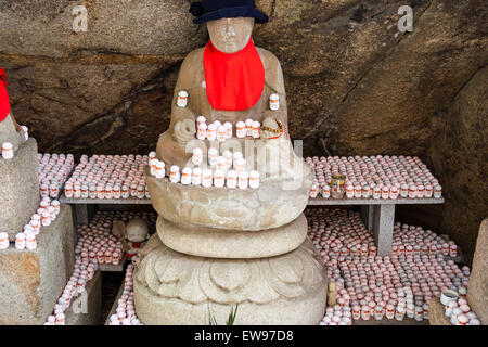 Große japanische Jizo, AKA Ojizo-sama, Jizo bosatsu, Statue mit Hunderten von kleinen hinter auf Racks am Senkoji Tempel, Onomichi, Japan. Stockfoto