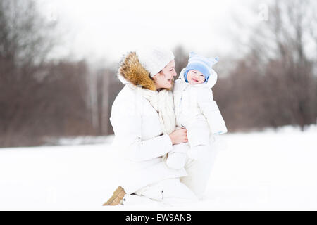 Junge attraktive Frau mit ihrem Baby in einem verschneiten Park spielen Stockfoto